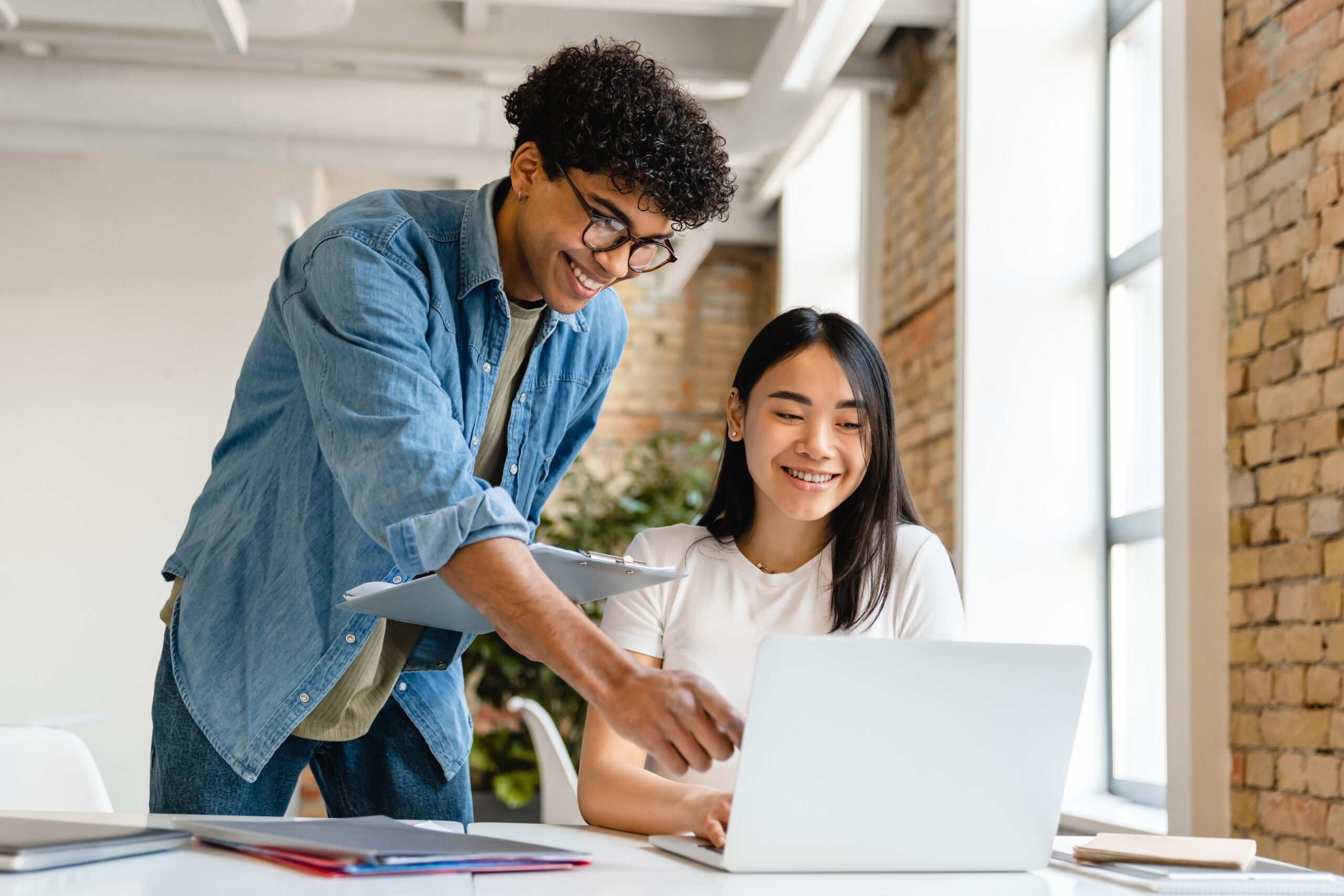 Two happy young sales intern sitting with a laptop.
